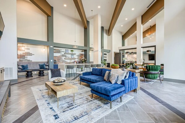 A spacious living area with a blue sofa, a coffee table, and a kitchen in the background.