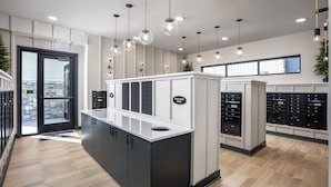 A modern hotel lobby with a reception desk, a glass door entrance, and a view of the outside. - Landing | Spectacular 1BD, Clubhouse, Yoga Studio (Broomfield)