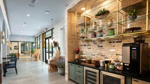 A modern kitchen with a brick wall, glass shelves, and a coffee machine. - Landing | Beautiful 1BD, Game Room (Houston)