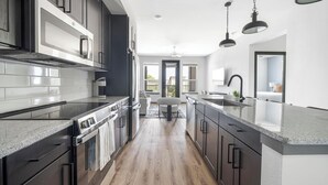 Una cocina moderna con armarios oscuros, electrodomésticos de acero inoxidable y una isla grande con fregadero.