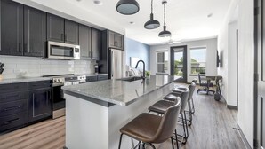 Una cocina moderna con armarios oscuros, una isla grande con taburetes de bar y un comedor con vistas.