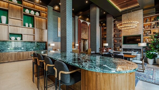 Una cocina moderna con una isla central, taburetes de bar y una zona de estar con chimenea.