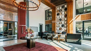 Un interior moderno con una mesa redonda, sillas, un perchero lleno de sombreros y una lámpara decorativa.