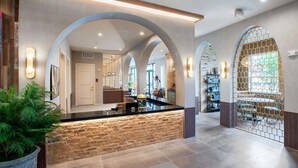 A spacious lobby with a central island, arched ceilings, and a view into the dining area. - Landing | Spectacular 1BD, Game Room (Houston)