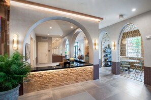 Eine großzügige Lobby mit einer zentralen Insellounge, gewölbten Decken und Blick ins Restaurant.