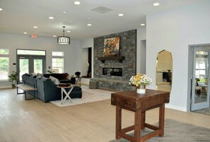 A spacious living area with a fireplace, sofas, a coffee table, and a view of the outdoors. - Landing | Amazing 2BD, Clubhouse, Pool (Ooltewah)