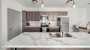 A modern kitchen with dark wooden cabinets, stainless steel appliances, and a marble countertop. - Landing | Amazing 2BD, Clubhouse, Pool (Ooltewah)
