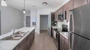A modern kitchen with stainless steel appliances, a marble countertop, and wooden cabinets. - Landing | Amazing 2BD, Clubhouse, Pool (Ooltewah)