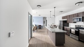 A modern kitchen with a central island, stainless steel appliances, and pendant lighting. - Landing | Beautiful 2BD, Pool, Clubhouse (Ooltewah)