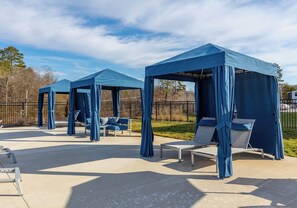 A covered outdoor seating area with lounge chairs and a table. - Landing | Beautiful 2BD, Pool, Clubhouse (Ooltewah)