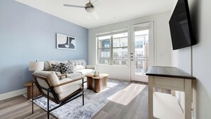 A modern living room with a sofa, coffee table, and a TV mounted on the wall. - Landing | Stylish 1BD, Clubhouse (Austin)