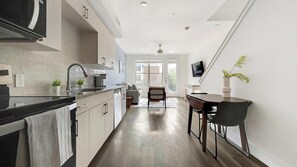 A modern kitchen with a dining area, a TV mounted on the wall, and a ceiling fan. - Landing | Stylish 1BD, Clubhouse (Austin)