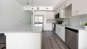 A modern kitchen with white cabinetry, stainless steel appliances, and a granite countertop. - Landing | Stunning 1BD, Clubhouse (Austin)