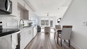 A modern kitchen with a black countertop, white cabinets, and a built-in microwave. - Landing | Modern 1BD, Clubhouse (Austin)