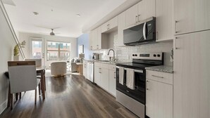 Eine moderne Küche mit hellen Holzschränken, Edelstahlgeräten und Blick ins Freie.