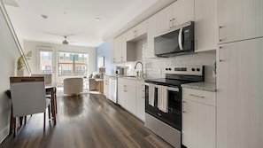 A modern kitchen with light wood cabinets, stainless steel appliances, and a view to the outside. - Landing | Stylish 1BD, Clubhouse (Austin)