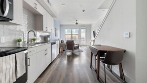 A modern kitchen with a dining area, a ceiling fan, and a view of the outside. - Landing | Chic 1BD, Clubhouse (Austin)