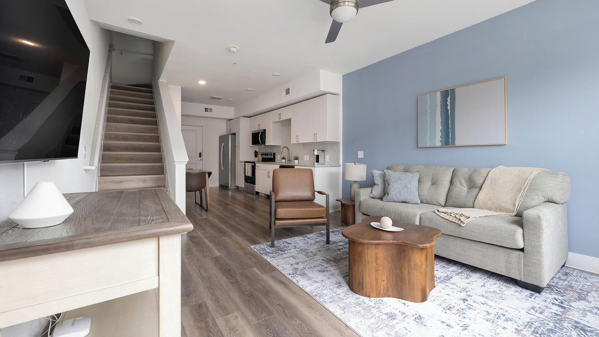 Een moderne woonkamer met een bank, salontafel en een televisie op een dressoir.