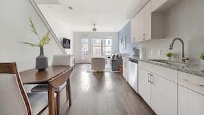 A modern kitchen with a dining area, wooden flooring, and a view to the outside. - Landing | Stunning 1BD, Clubhouse (Austin)