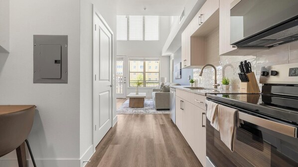 A modern kitchen with a built-in oven, stainless steel appliances, and a window overlooking a cityscape. - Landing | Chic 1BD, Clubhouse (Austin)