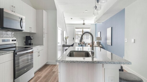 A modern kitchen with stainless steel appliances, a granite countertop, and a view into the living area. - Landing | Amazing 1BD, Clubhouse (Austin)