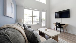 Ein modernes Wohnzimmer mit einer Couch, einem Couchtisch, einem Fernseher und einem Schreibtisch.
