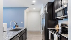 Una cocina moderna con encimeras de granito, electrodomésticos de acero inoxidable y una pared de acento azul.