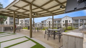Un patio al aire libre con zona de estar cubierta, una parrilla y una mesa de billar.