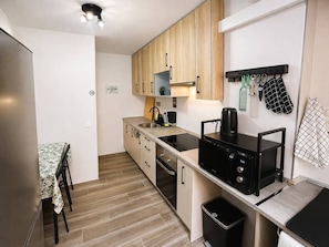 Una cocina compacta con gabinetes de madera, un microondas negro y un lavamanos.