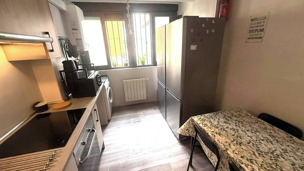 A compact kitchen with a refrigerator, stove, and sink. - Room-cozy Guest Room in Central Madrid - (Madrid)