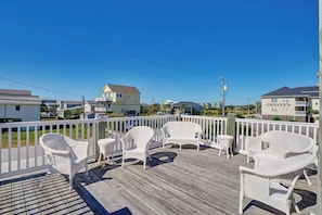 A wooden deck with wicker chairs and a small table, overlooking a residential area with houses and a building labeled 'TIFFANY'S'.