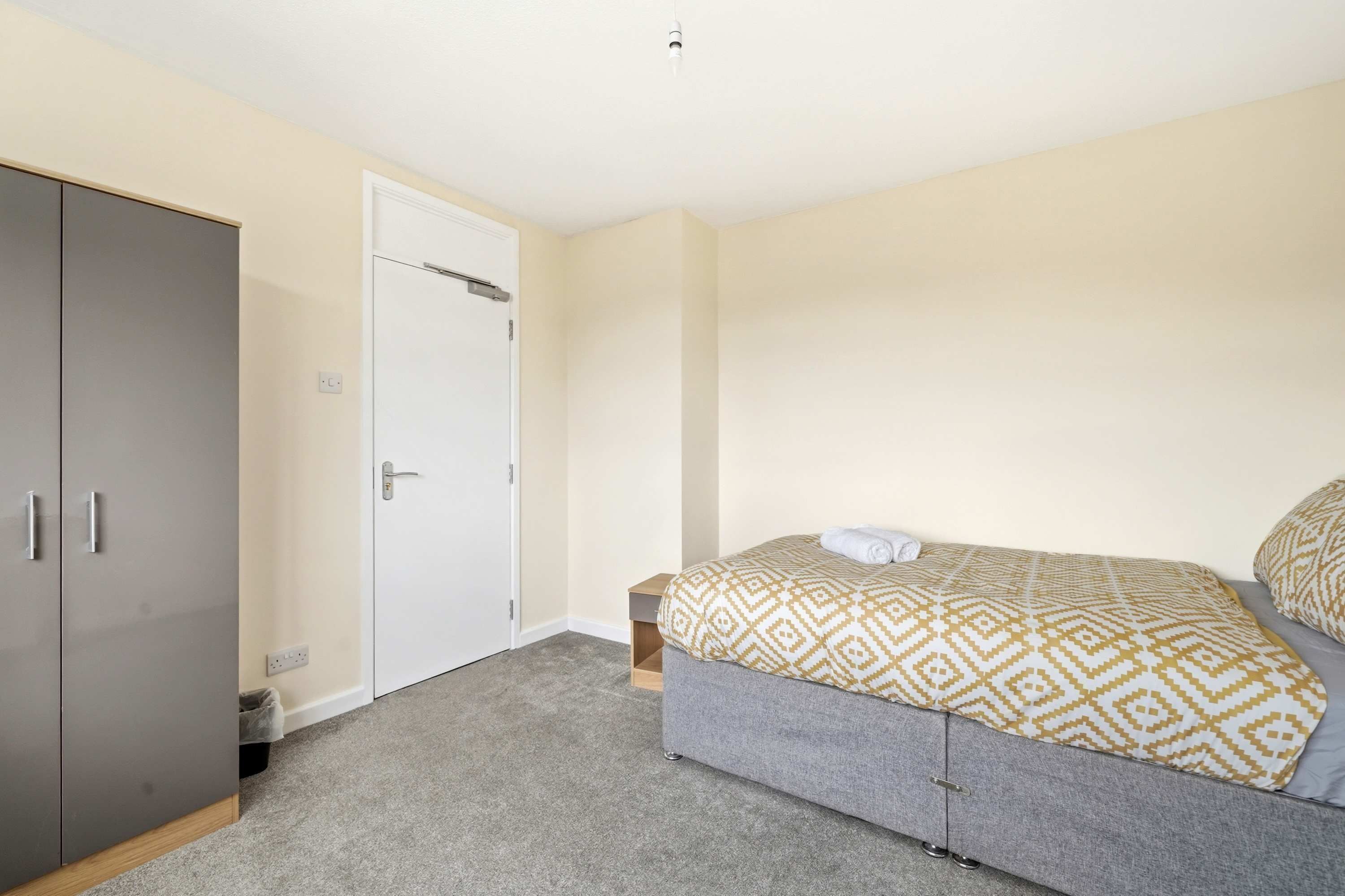 A bedroom with a bed, a wardrobe, and a door.