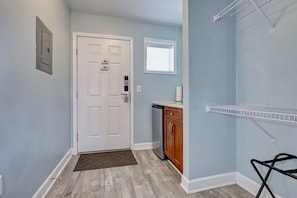 A hallway with a white door, a small window, a kitchen area with a dishwasher, and a metal shelf. - Surf City Beach Stay – Seaside Escape motel unit (Surf City)