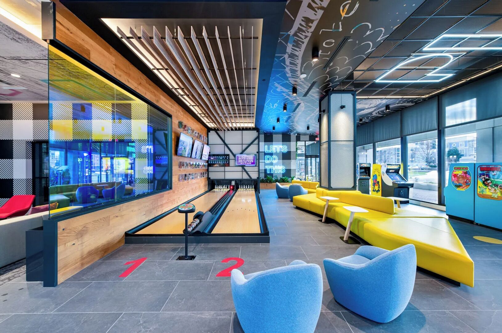 A bowling alley with a wooden floor, neon lights, and seating areas.