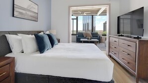 Quarto de hotel moderno com uma cama grande, televisão, cômoda e vista para a cidade.