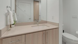 Ein Badezimmer mit Waschbecken, Spiegel, Handtuchhalter und Toilette.