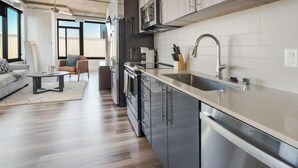 Una cocina moderna con electrodomésticos de acero inoxidable, un ventanal grande y una zona de comedor con sofá y mesa.
