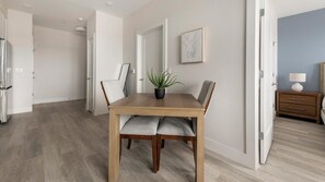 A dining area with a wooden table, chairs, a potted plant, and a framed picture on the wall. - Landing | Incredible 1BD in Columbia Heights (Washington)