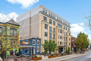 A multi-story building with a flat facade, large windows, and a ground-level commercial space with outdoor seating. - Landing | Incredible 1BD in Columbia Heights (Washington)