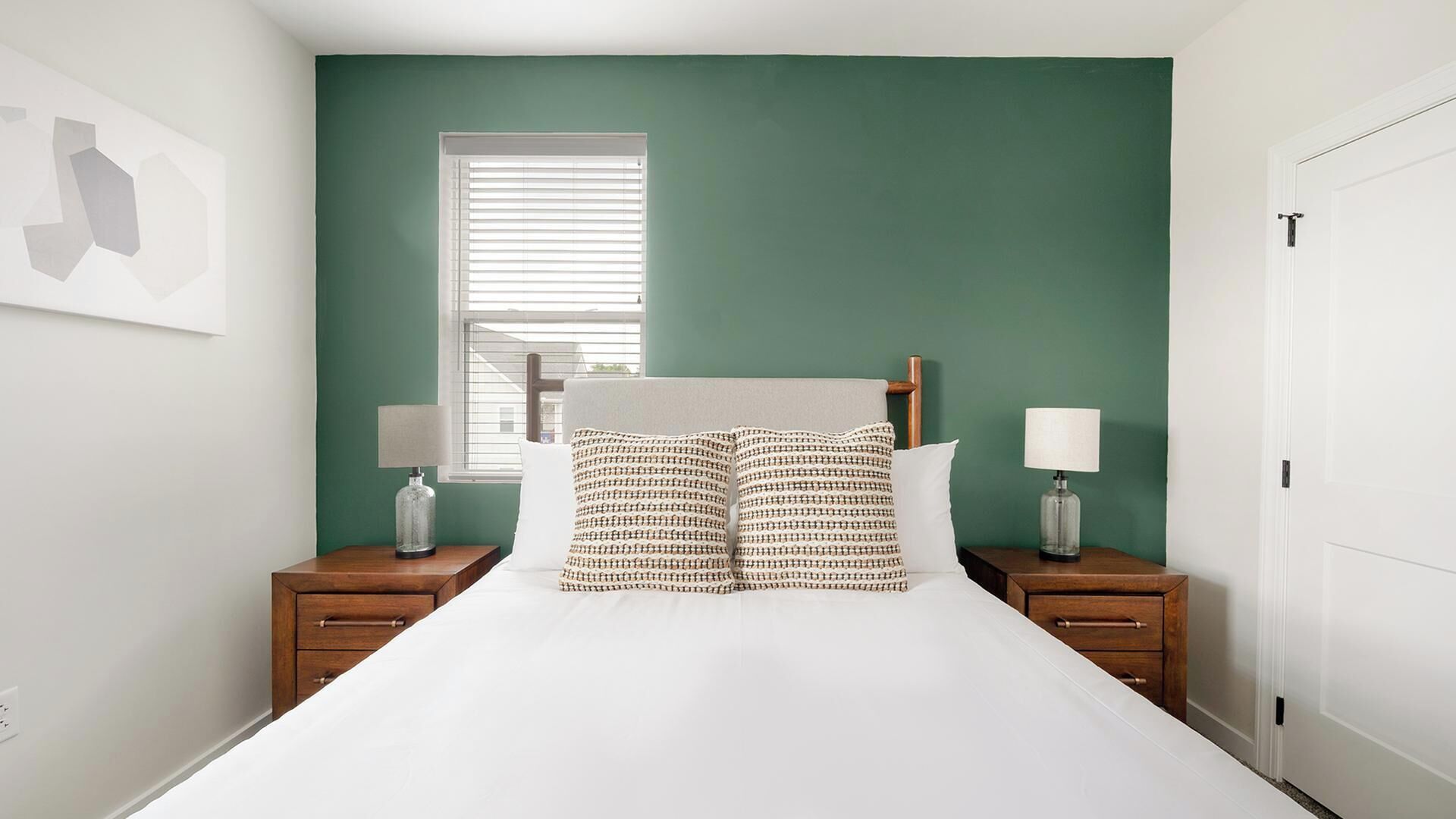 A bedroom with a bed, two nightstands, a window, and a door.