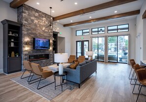 A spacious lobby with a stone fireplace, comfortable seating, a television, and large windows offering views. - Landing | Spectacular 2BD, Gym (Knoxville)