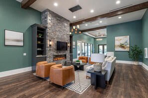 A modern living room with a stone fireplace, leather seating, and a flat-screen TV. - Landing | Modern 2BD, Gym (Knoxville)