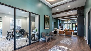Een modern interieur met een glazen scheiding tussen een eetgedeelte en een woonruimte, houten vloeren en uitzicht door grote ramen.