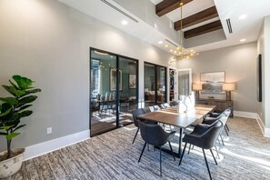 A modern dining area with a long table, chairs, and a potted plant. - Landing | Stylish 1BD, Gym (Knoxville)