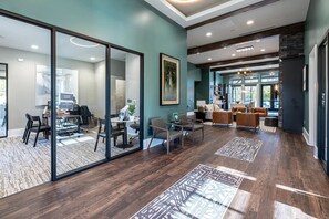 A modern interior with a glass partition separating a dining area from a living space, wooden flooring, and a view through large windows. - Landing | Stylish 1BD, Gym (Knoxville)
