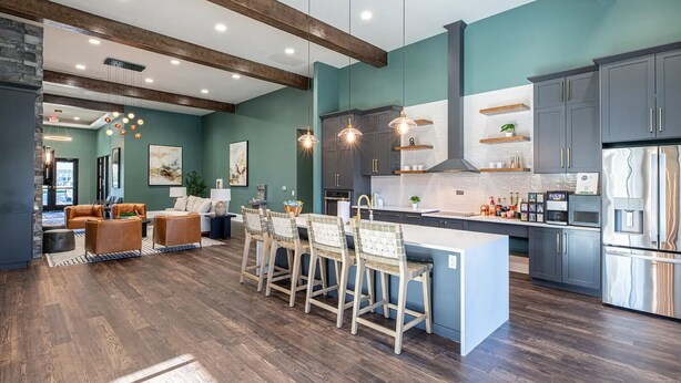 Una cocina moderna con una isla central, pisos de madera oscura y un comedor con sillas y una mesa.