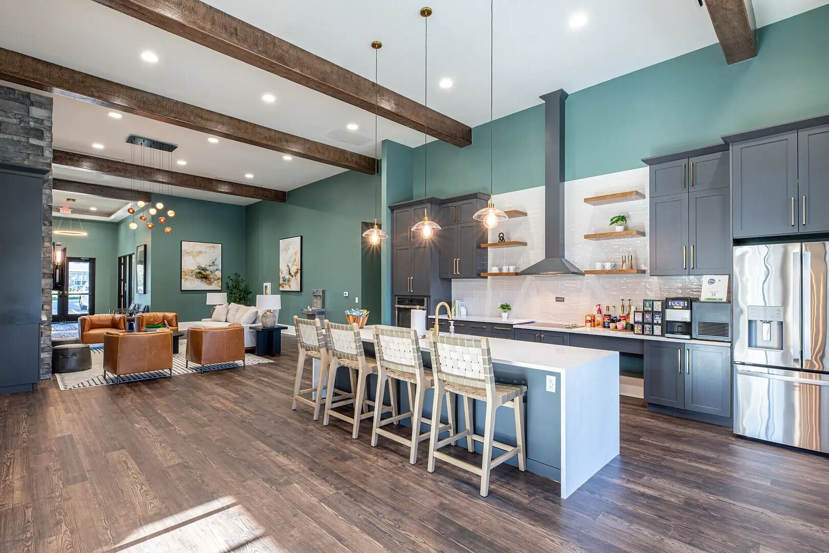 A modern kitchen with a central island, dark wooden floors, and a dining area with chairs and a table.