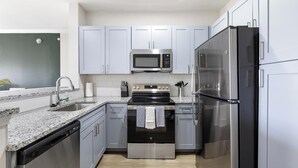 A modern kitchen with stainless steel appliances, a dishwasher, and granite countertops. - Landing | Spectacular 2BD, Gym (Garland)