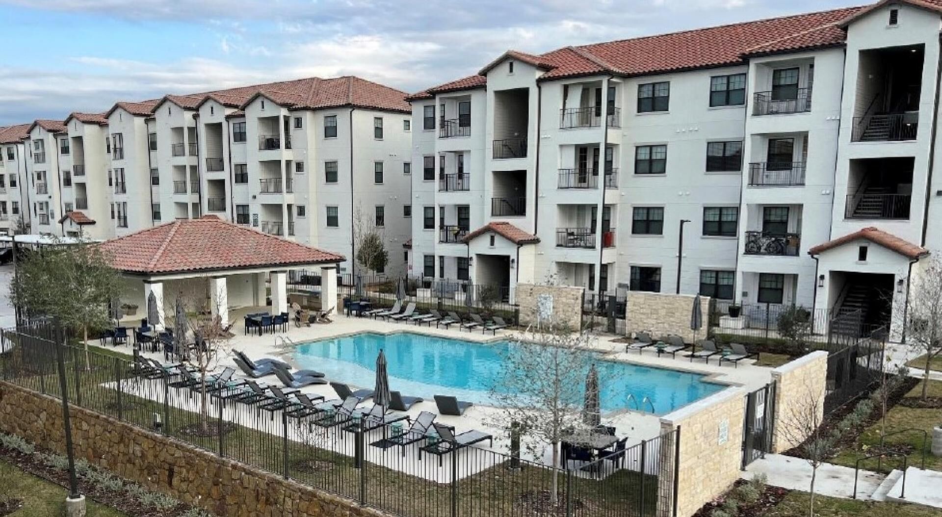 A residential building with a swimming pool, balconies, and a covered patio area.
