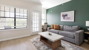 Ein Wohnzimmer mit grauem Sofa, einem Couchtisch und einem Teppich.